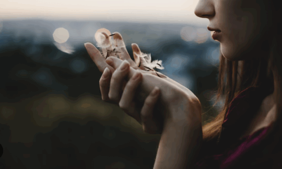 Woman blowing flower seeds on a Sacred Pause