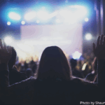 Woman raising hands in worship at concert copy