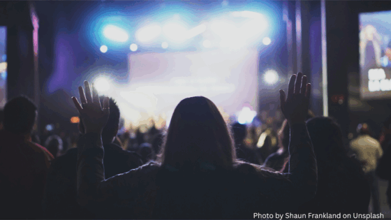 Woman raising hands in worship at concert copy
